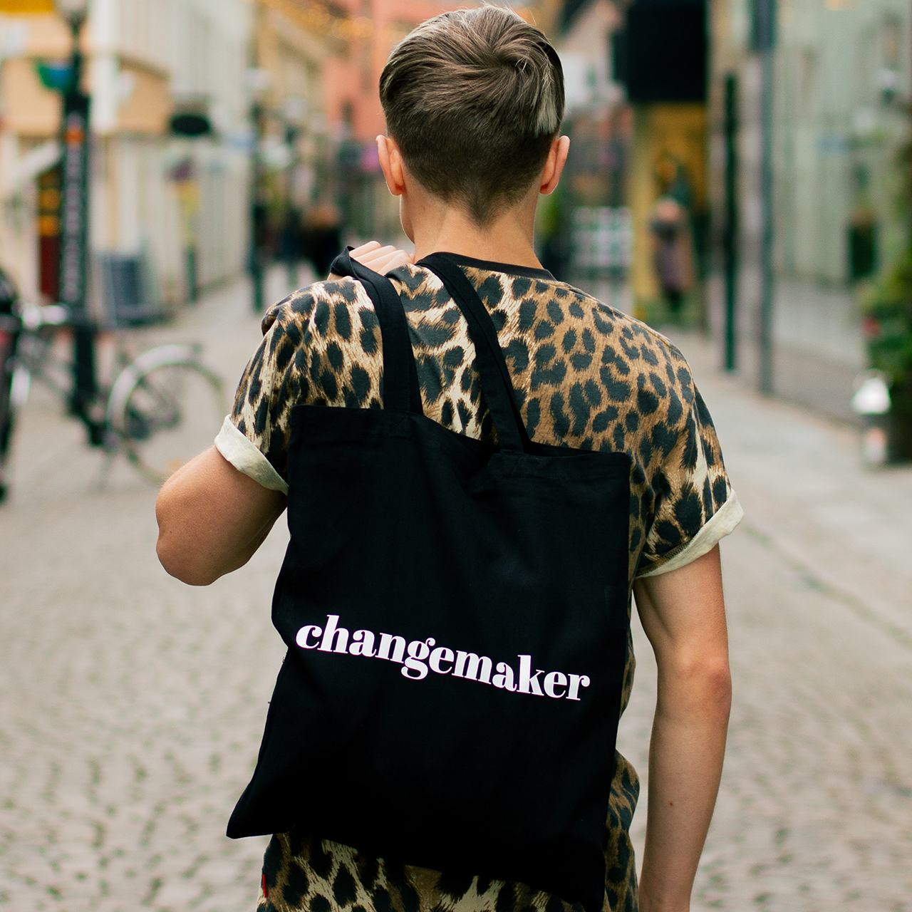 Tygkasse Changemaker, hänger över axeln på modell i stadsmiljö