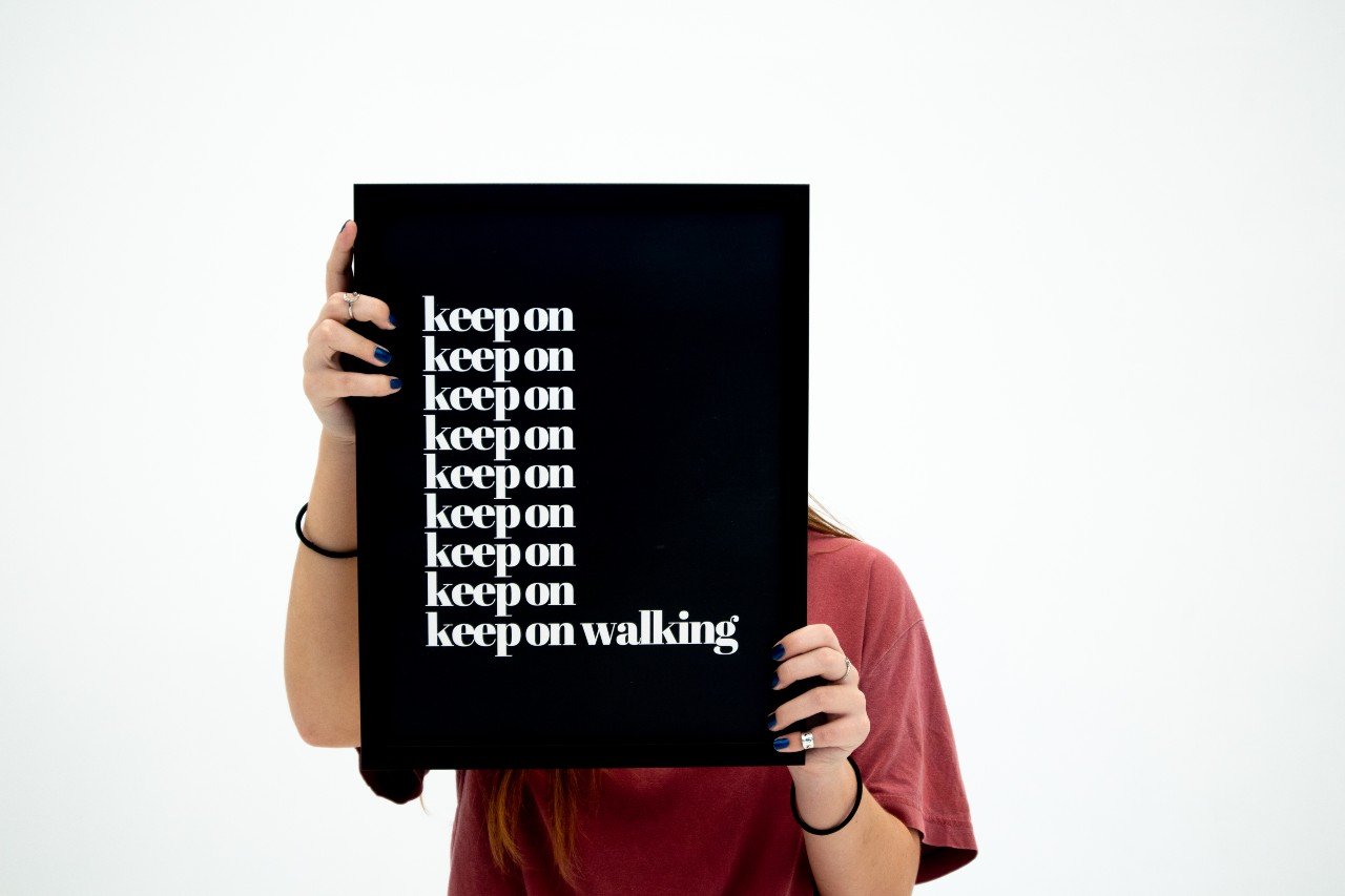 Poster Keep on walking hålls upp av en person som skyms bakom postern