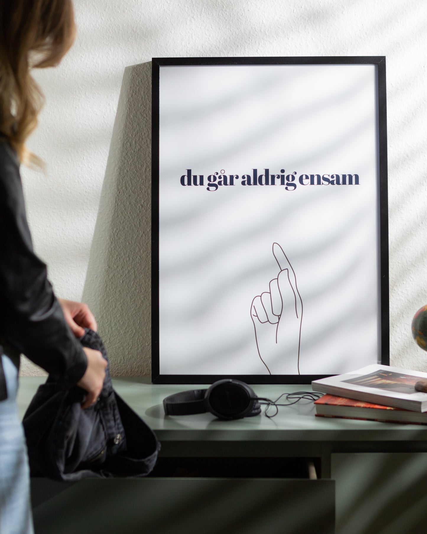 Poster du går aldrig ensam inramad på byrå. Någon packar ner kläder i en byrålåda.