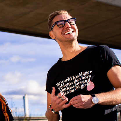 T-shirt The World has Bigger Problems, modell med svarta glasögon står under en bro  med industrier i bakgrunden