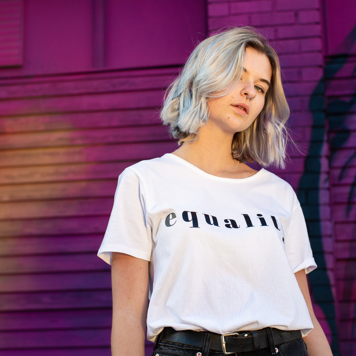 T-shirt Equality, kvinnlig modell med vit t-shirt framför rosa vägg