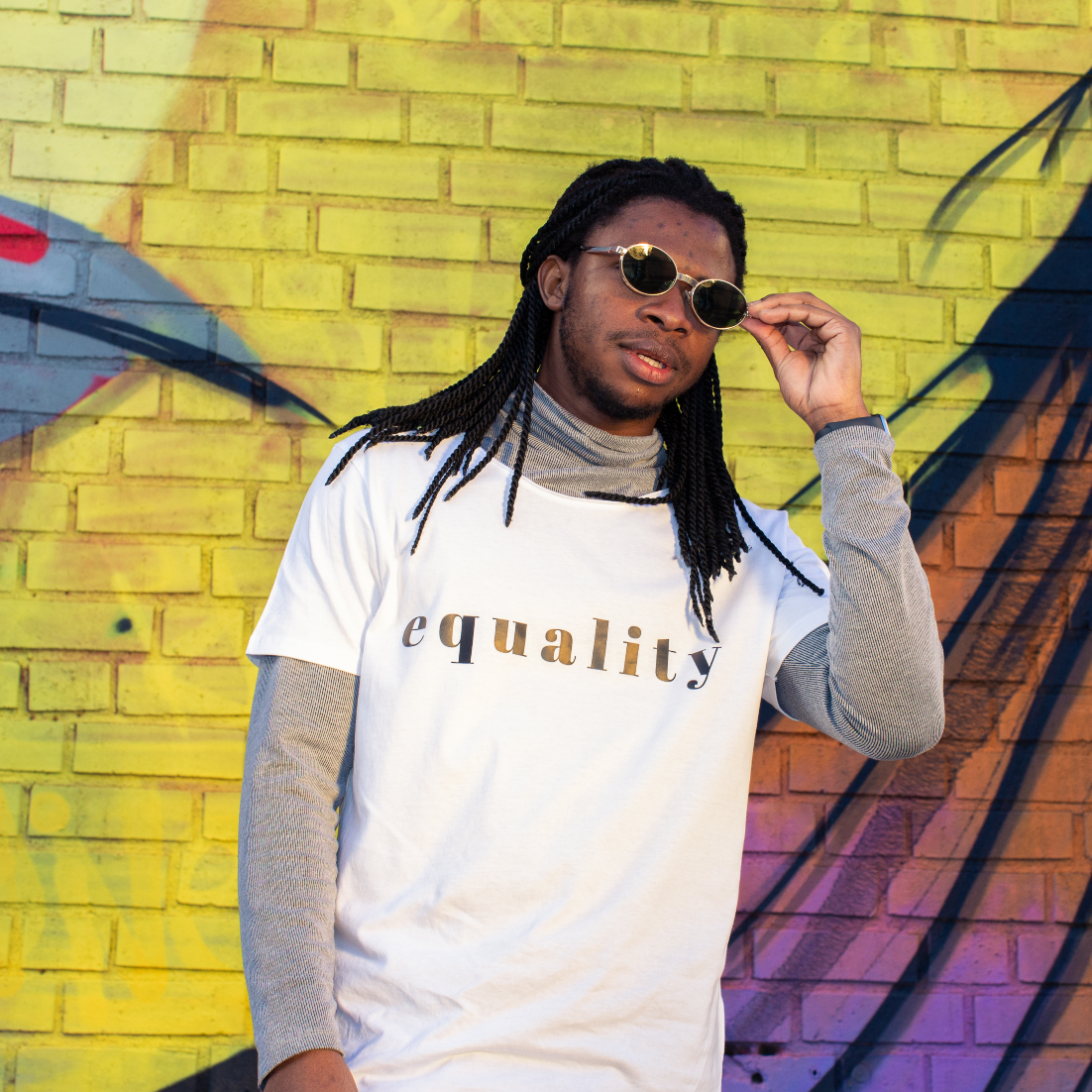 T-shirt Equality, manlig modell med vit t-shirt framför gul vägg