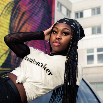 T-shirt Changemaker. Kvinnlig modell ligger på en motorhuv med en vägg med graffiti i bakgrunden