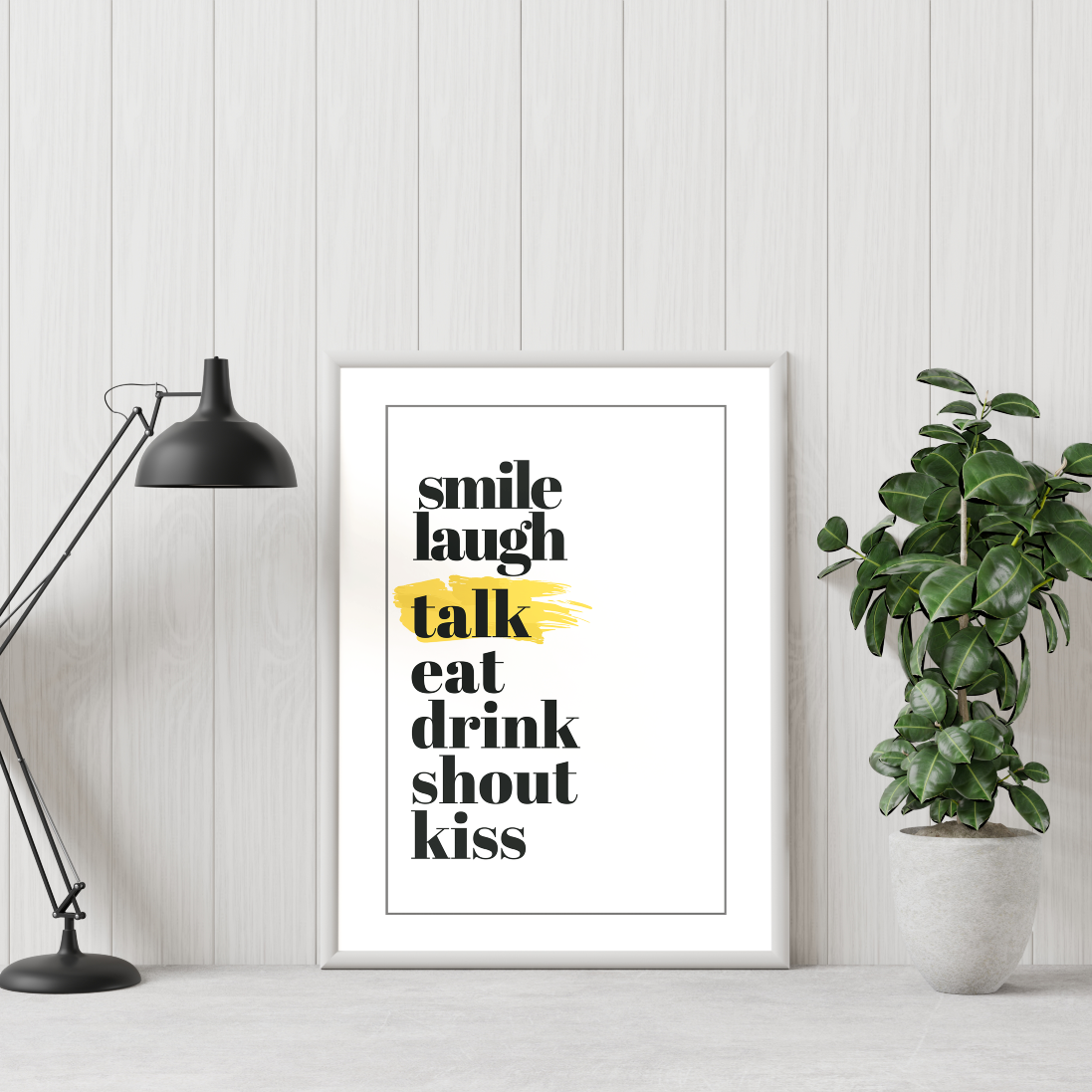 Poster sju budord inramad mot vit vägg, en grön växt till höger och en skrivbordslampa till vänster