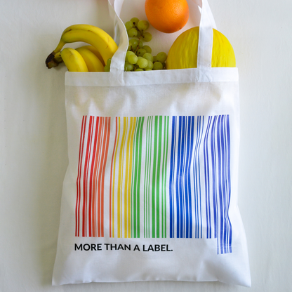 Tygkasse more than a Label, fyll med frukter, mot vit bakgrund.