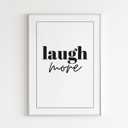 Poster Laugh more, vit med svart text, inramad mot vit vägg.