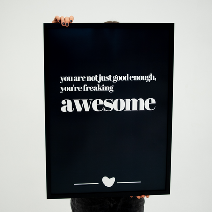 Poster Freaking Awesome inramad hålls upp en person med svarta naglar.