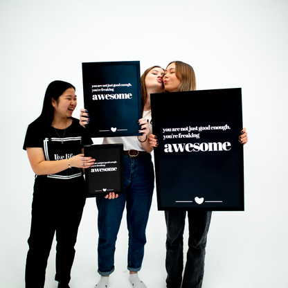 Poster Freaking awesome tre storlekar och inramade hålls upp av tre personer