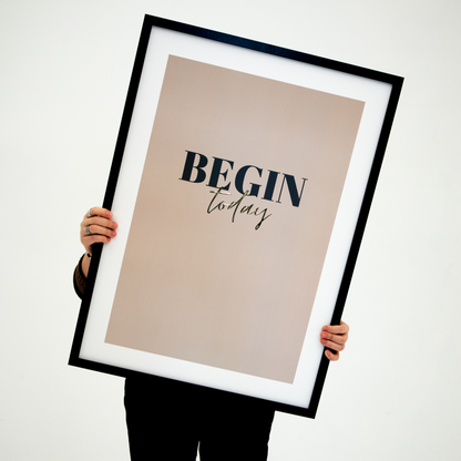 Poster Begin today, inramad. En person håller upp tavlan framför sig.