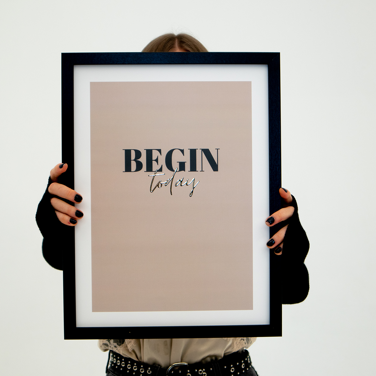 Poster begin today, inramad. En person håller upp tavlan så att ansiktet skyms.