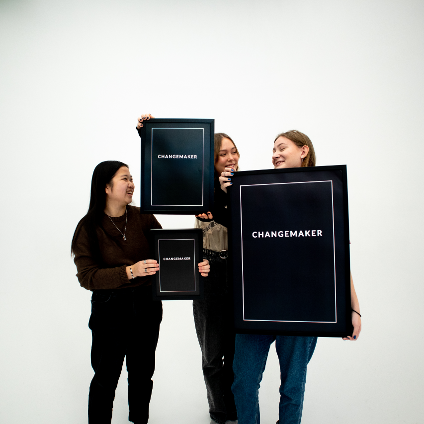 Poster Changemaker.  alla tre storlekarna inramade hålls upp av tre personer.
