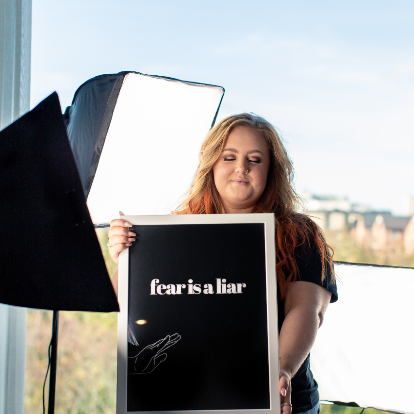 Poster Fear is a liar inramad, hålls upp vid starka fotolampor