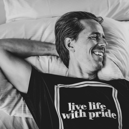 T-shirt Live Life modell ligger i sängen med en arm under huvudet.