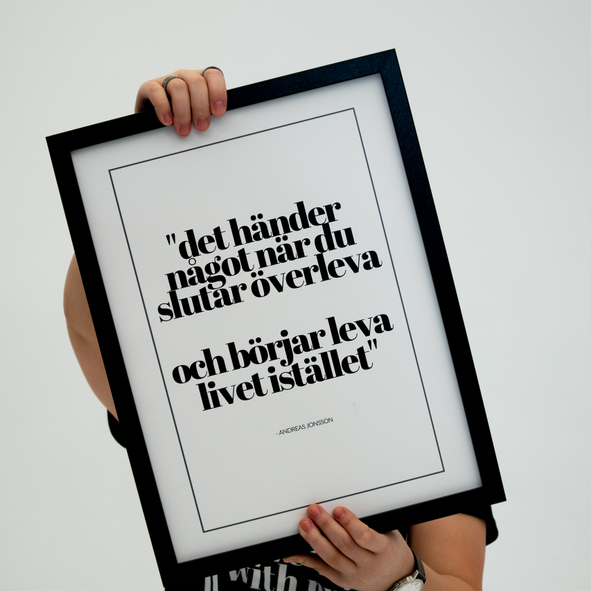 Poster Det händer något, inramad. Hålls upp av en person som skyms av tavlan