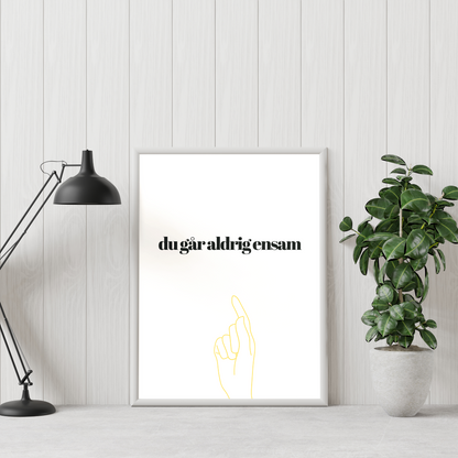 Poster Du går aldrig ensam mot vi vägg, grön växt till höger och skrivbordslampa till vänster