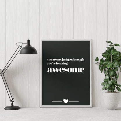 Poster freaking awesome inramad mot vit vägg. En grön växt till höger och skrivbordslampa till vänster