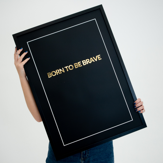 Poster Born to be brave, inramad. En person håller upp tavlan framför sig.