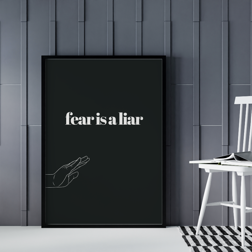 Poster Fear is a liar inramad mot grå bakgrund, till höger syns en vit stol