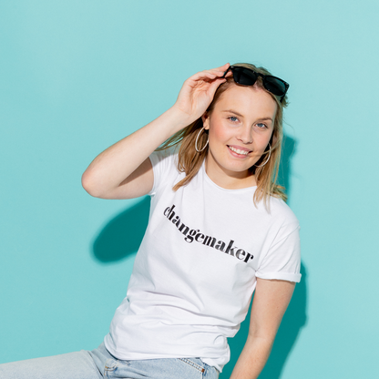 T-shirt Changemaker. Kvinnlig modell i vit t-shirt framför en turkos bakgrund