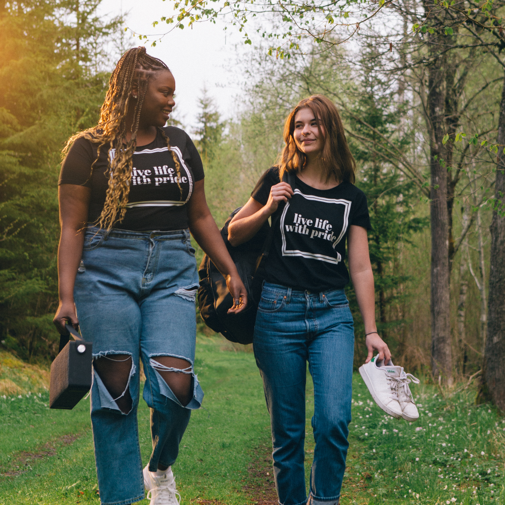 T-shirt Live life två modeller, en barfota och en med en högtalare i handen går på skogstig med solen i bakgrunden