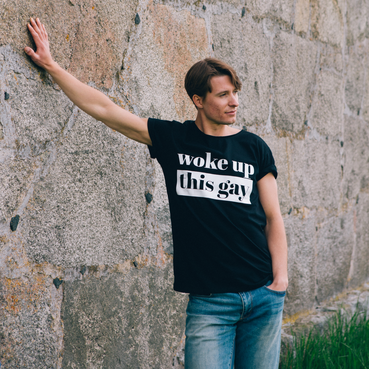 T-shirt Woke up this Gay,  modell lutar sig mot gammal stenvägg