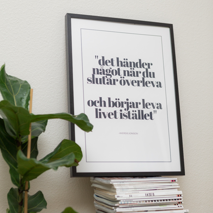 Poster Det händer något, inramad, ståendes på en trave magasin . I förgrunden syns en grön växt