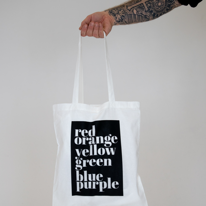 Tygkasse Rainbow hålls upp mot vit bakgrund