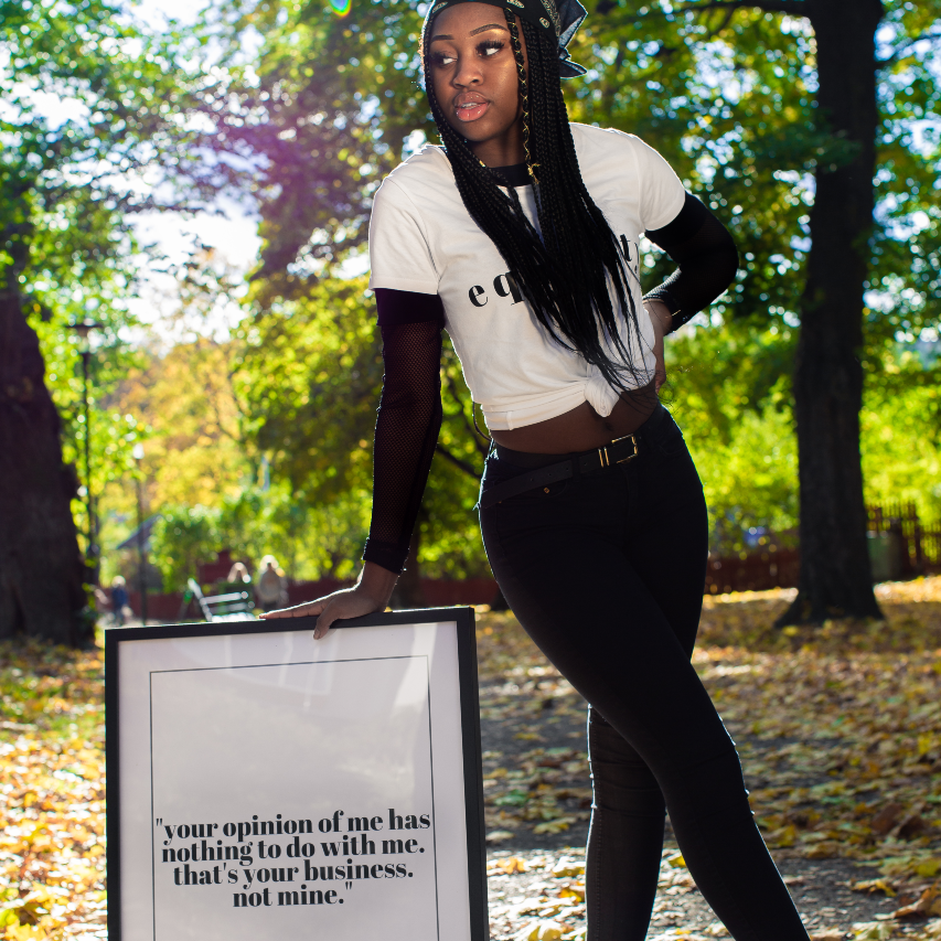 Poster Your opinion inramad. En ung kvinna står i en park och lutar sig lätt mot sidan av ramen.